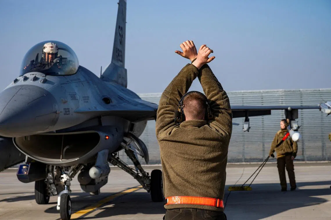 A US Air Force airman marshals an F-16 Fighting Falcon aircraft at an air base in Romania.
