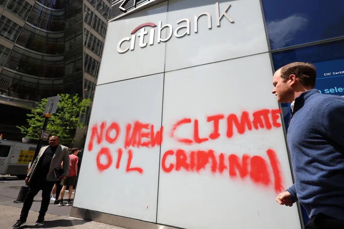 People walk past a spray-painted message left by climate protestors on the outside of a Citibank branch in Midtown Manhattan in New York City, New York, U.S., April 24, 2023. REUTERS/Mike Segar