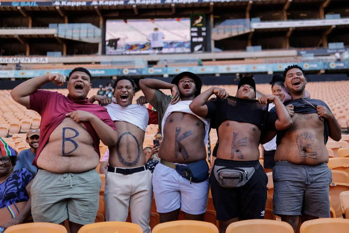 Springboks supporters lift their shirts revealing letters that spell the word "Bokke" as they gather with others ahead of the arrival of the South African rugby team during the Springboks Champions trophy tour in Johannesburg on Thursday after South Africa won the France 2023 Rugby World Cup final against New Zealand.