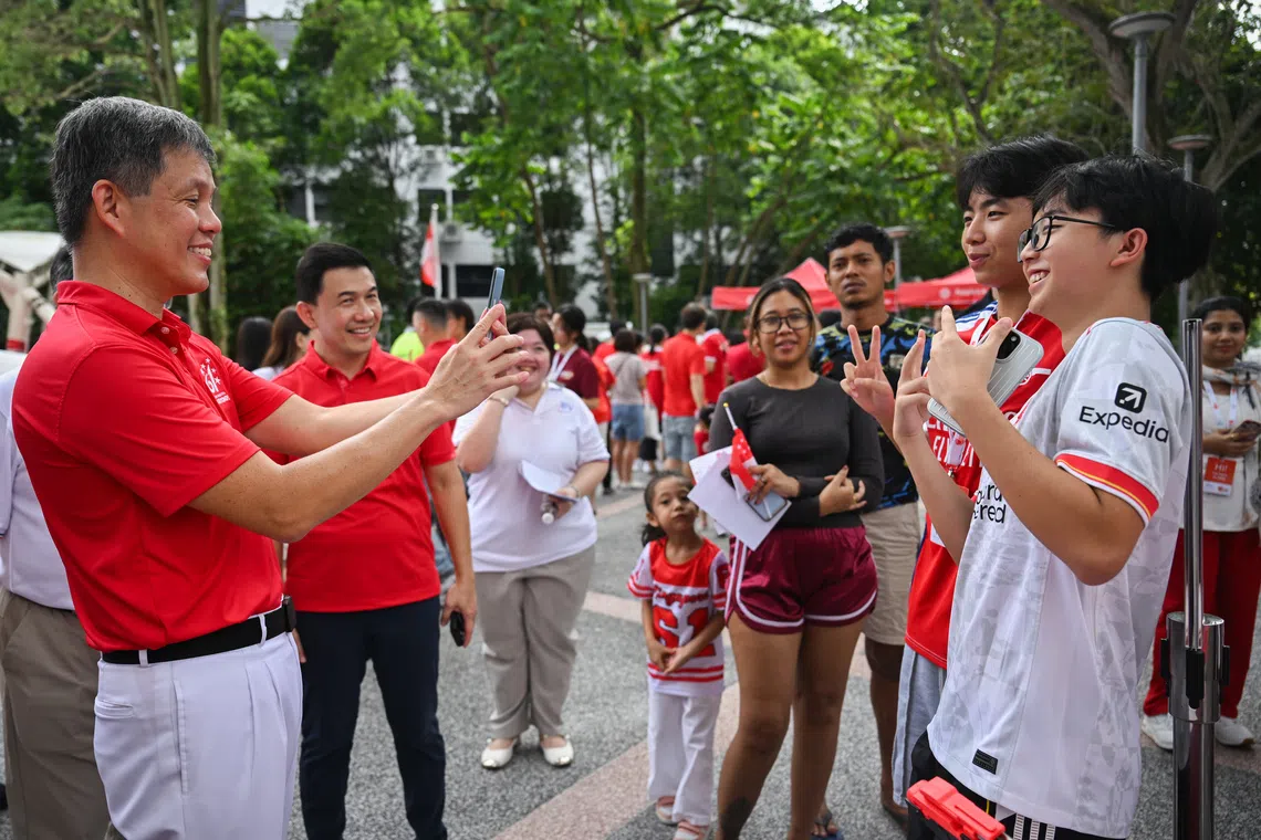 Defence Minister Chan Chun Sing taking a picture of Jonas Lee, 17, (white tee) and Gareth Chua, 17, for the BeReal trend, at the Buona Vista National Day Observance Ceremony on Aug 9.