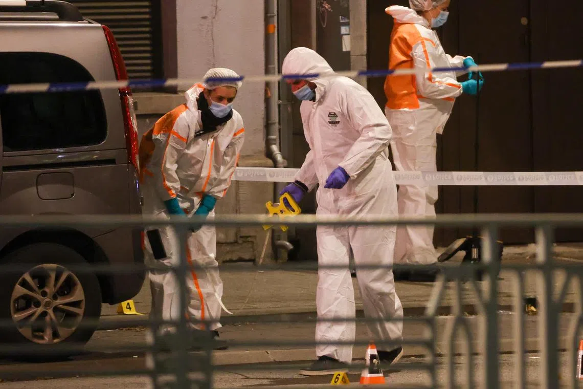 Belgian police and forensics officers work at the scene of the shooting in Brussels, Belgium.