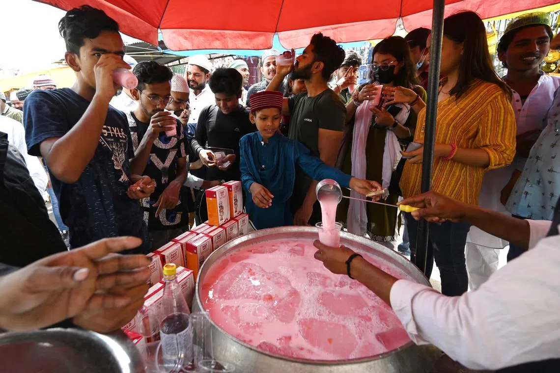 People drink a chilled flavoured beverage to cool off during a hot afternoon in the old quarters of Delhi on April 21, 2023.