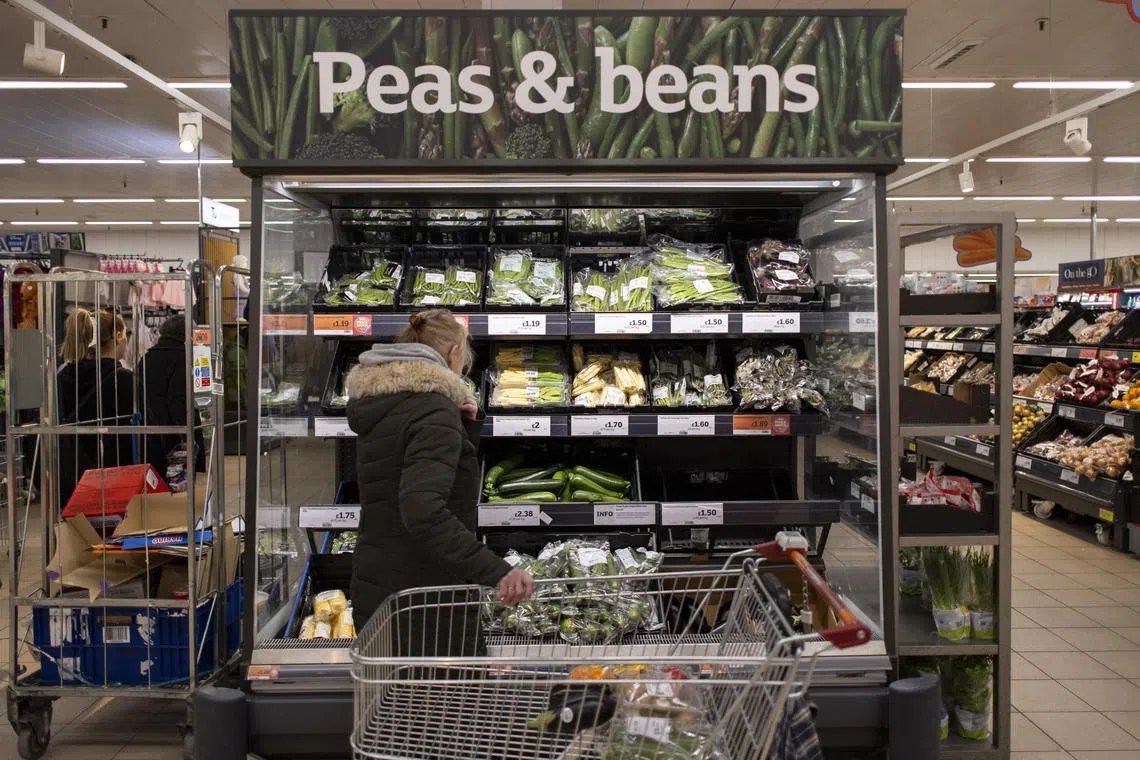 Customers shop for groceries at Sainsbury's supermarket in London.