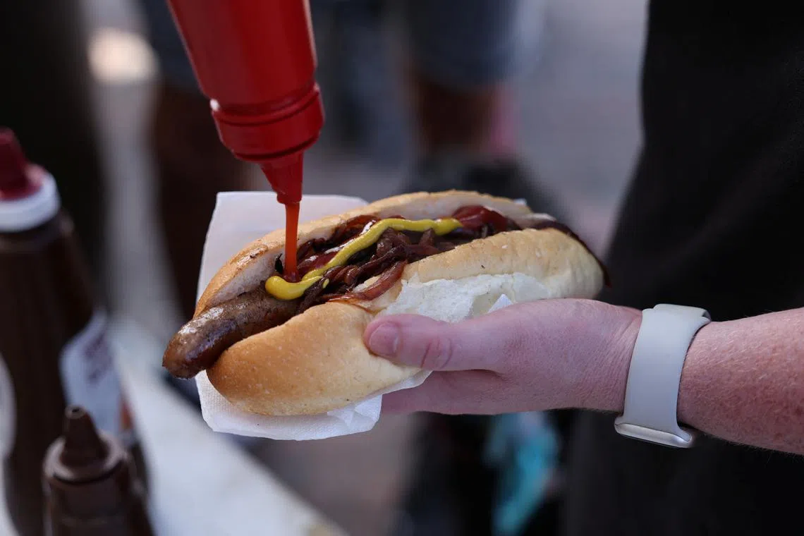 A voter puts ketchup on a so-called \"democracy sausage\" on the day of the Australian federal election, in Sydney, Australia, May 3, 2025. REUTERS/Hollie Adams