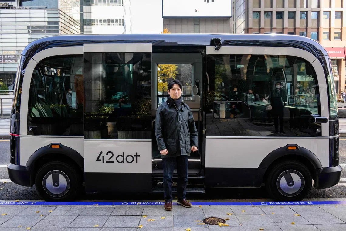 This photo taken in Seoul on November 23, 2022 shows Jeong Seong-gyun, head of automomous driving at 42 Dot, the start-up now owned by South Korea's Hyundai which created the technology for the country's first self-driving bus route, posing outside a self-driving bus in Seoul. - South Korea's capital launched its first self-driving bus route on November 25, part of an experiment which engineers said aims to make the public feel more comfortable with driverless vehicles on the roads. (Photo by Anthony WALLACE / AFP)