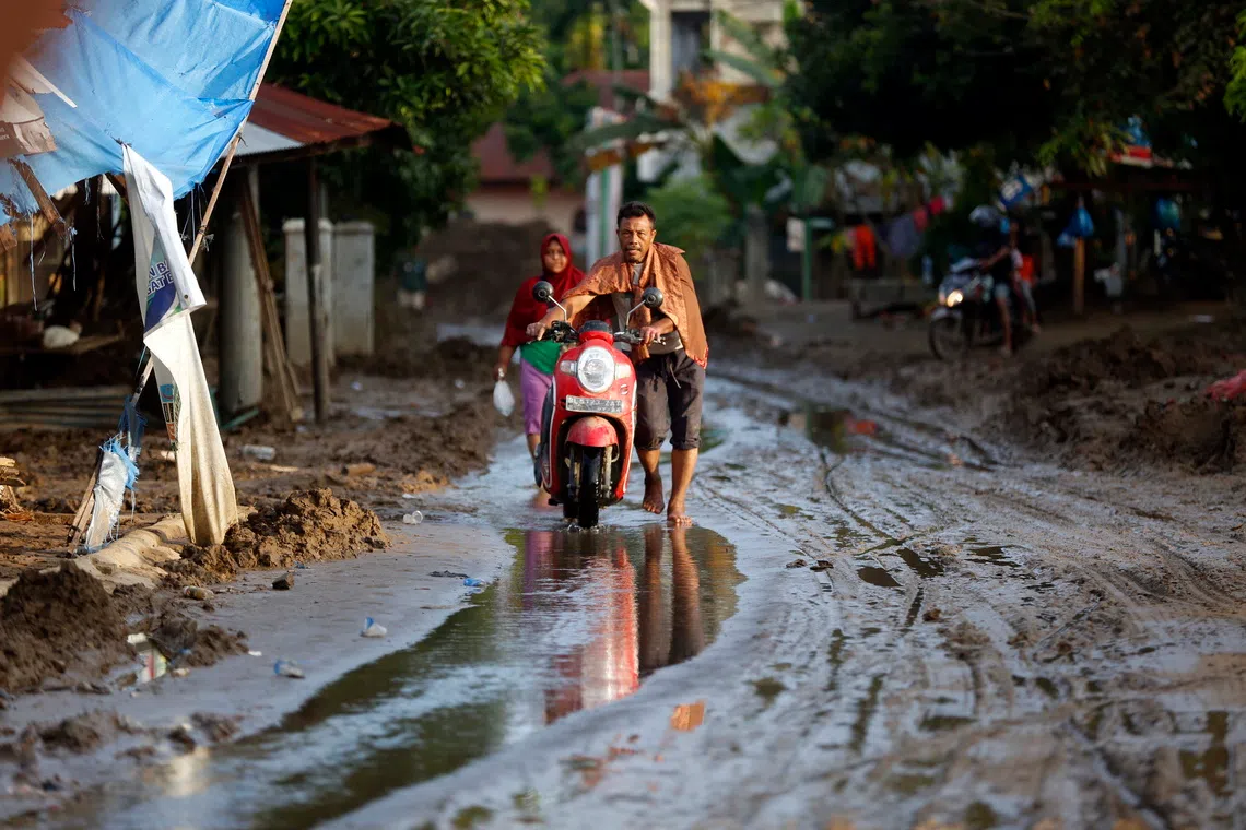 Residents walking through muddy roads in a flood-affected village in the Meureudu area, Pidie Jaya, Aceh, Indonesia, on Dec 2, 2025. 