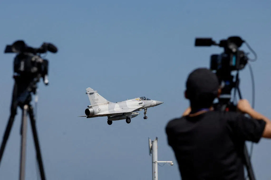 A member of the media takes a video of a Taiwan Air Force Mirage 2000 aircraft preparing to land at Hsinchu Air Base in Hsinchu, Taiwan October 14, 2024. REUTERS/Tyrone Siu