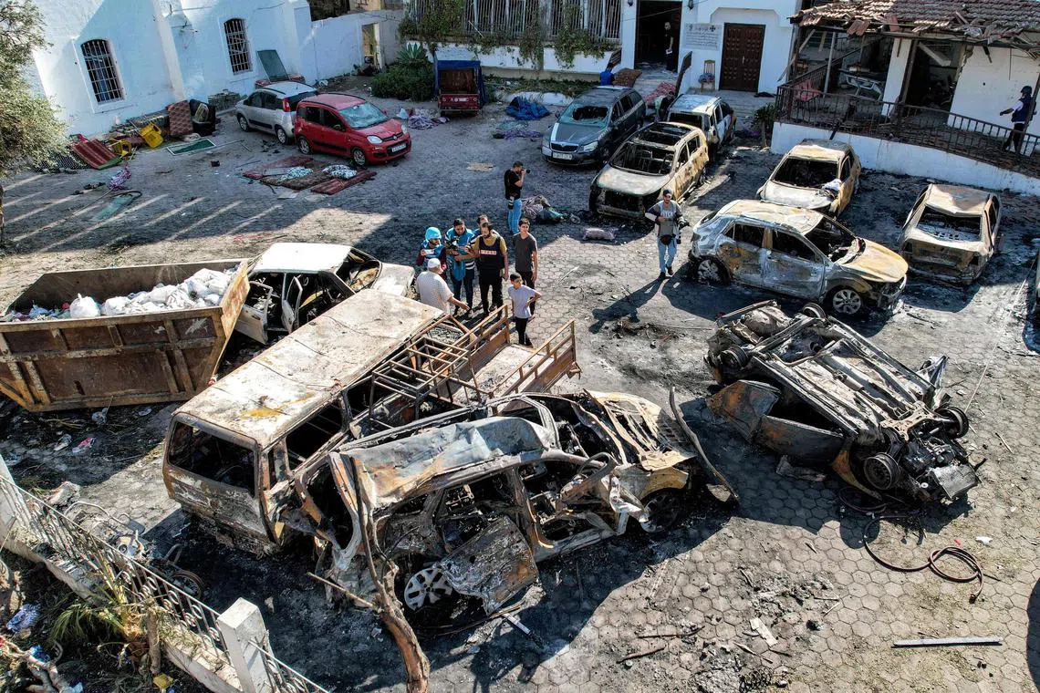 People stand before destroyed buildings at the site of the Ah Ahli Arab Hospital in central Gaza, in the aftermath of an overnight strike there.
