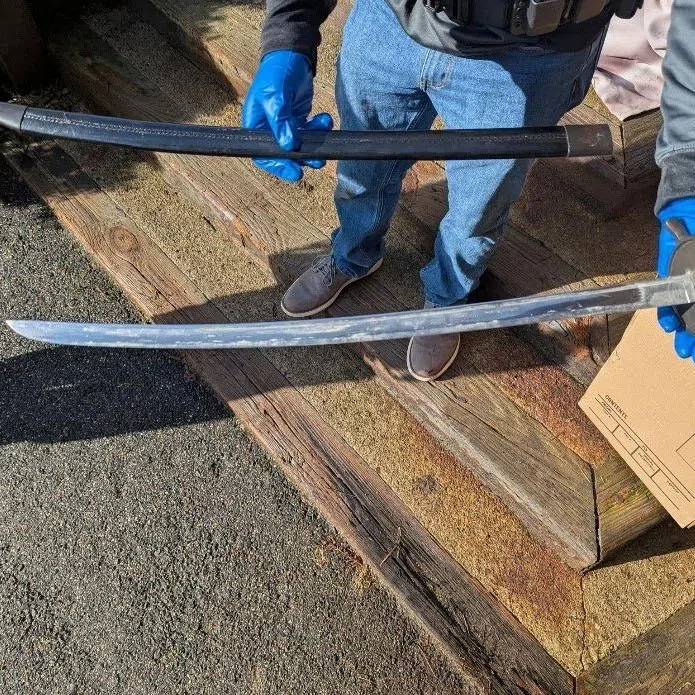 A law enforcement agent holds one of several bladed weapons seized by authorities after the arrest of Andrew Emerald in Great Barrington, Massachusetts, U.S., April 1, 2026, on charges that he threatened U.S. President Donald Trump in Facebook posts. U.S. Attorney's Office for the District of Massachusetts/Handout via REUTERS