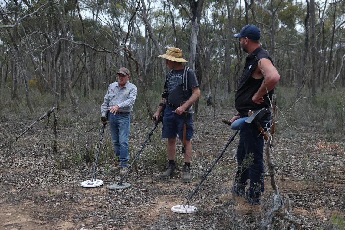 Mr Tony Mills (left), 72, from The Gold Centre, demonstrates to Mr Darren Gregoire, 62, and Mr Sam Randall, 45, how to use a metal detector during a gold-prospecting tour in Maryborough, Australia.