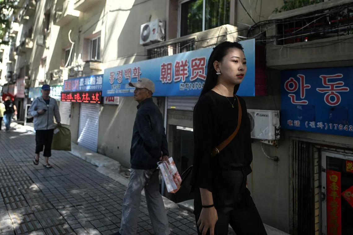 This photo taken on September 21, 2023 shows people walking down a street in the border city of Dandong, in China's northeastern Liaoning province. Stranded North Korean workers and merchants who rely on cross-border trade see scant signs that the frontier with China will reopen soon, despite recent trips abroad by leader Kim Jong Un and the country's athletes. (Photo by Pedro PARDO / AFP) / To go with "China-NKorea-diplomacy-health-trade-virus-labour", FOCUS by Matthew WALSH and Ludovic EHRET