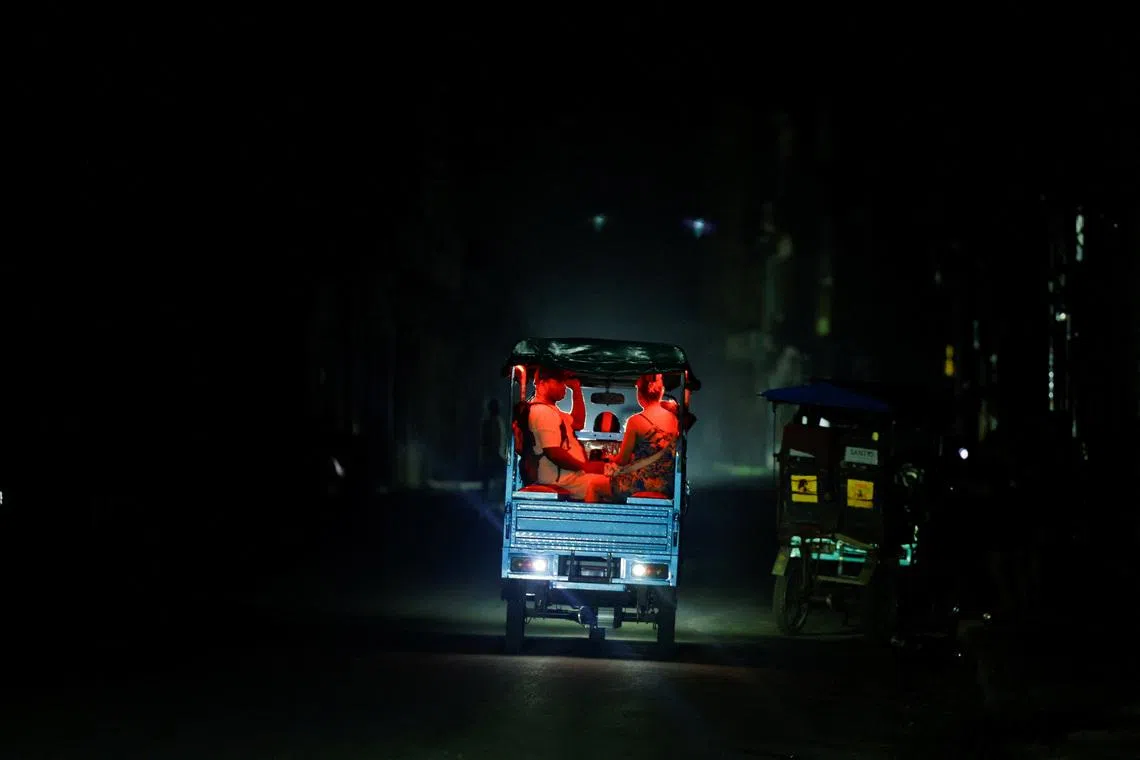 People ride an electric tricycle, one of the few modes of transportation still functioning, as Cuba's national power grid collapsed, marking the third major outage in nine days, in Havana, Cuba, July 14, 2026. REUTERS/Norlys Perez