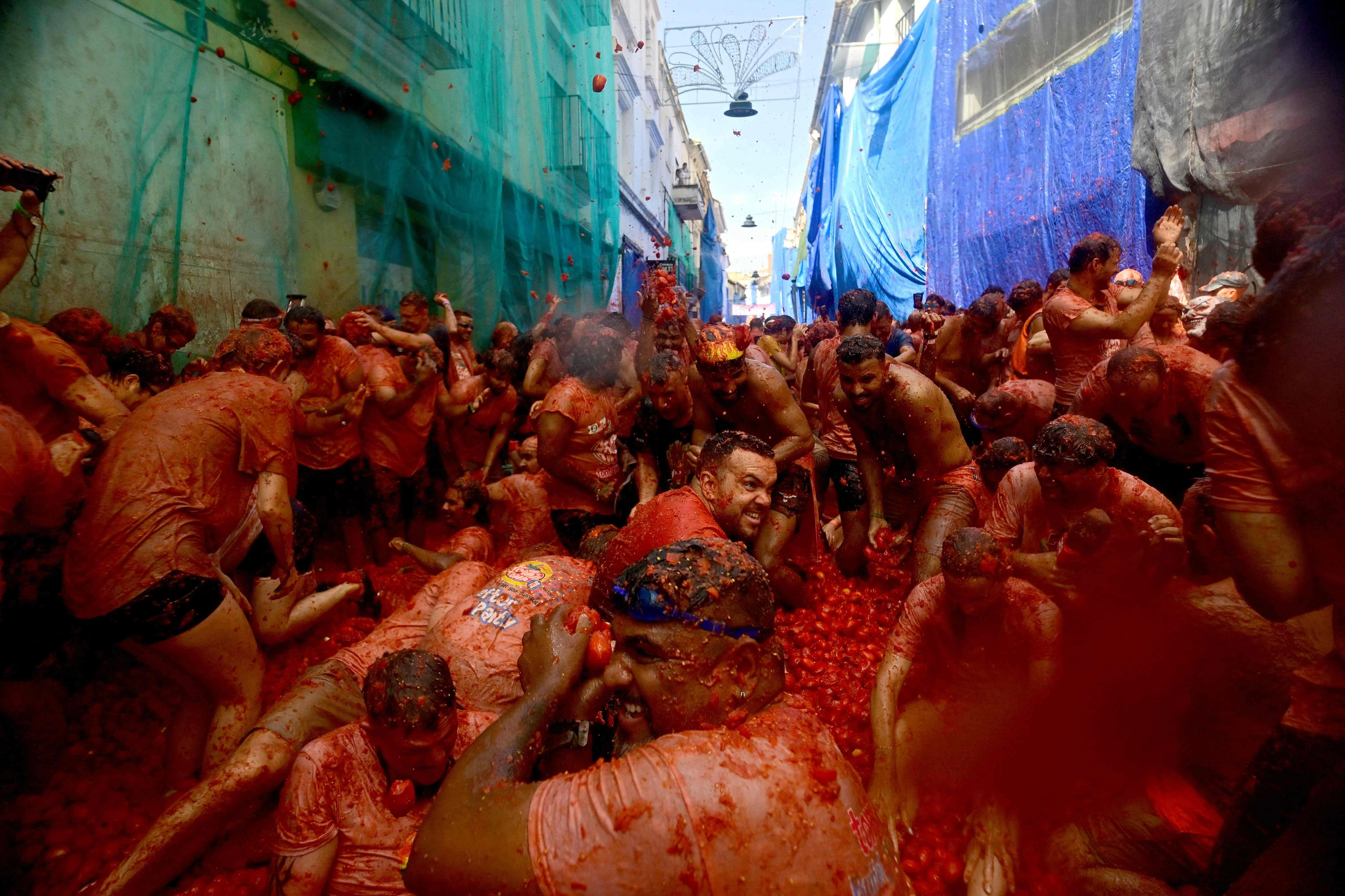 TOPSHOT - Revellers participate in the "Tomatina" annual food-battle in the Spanish eastern town of Bunol, on August 26, 2026. (Photo by Jose JORDAN / AFP)