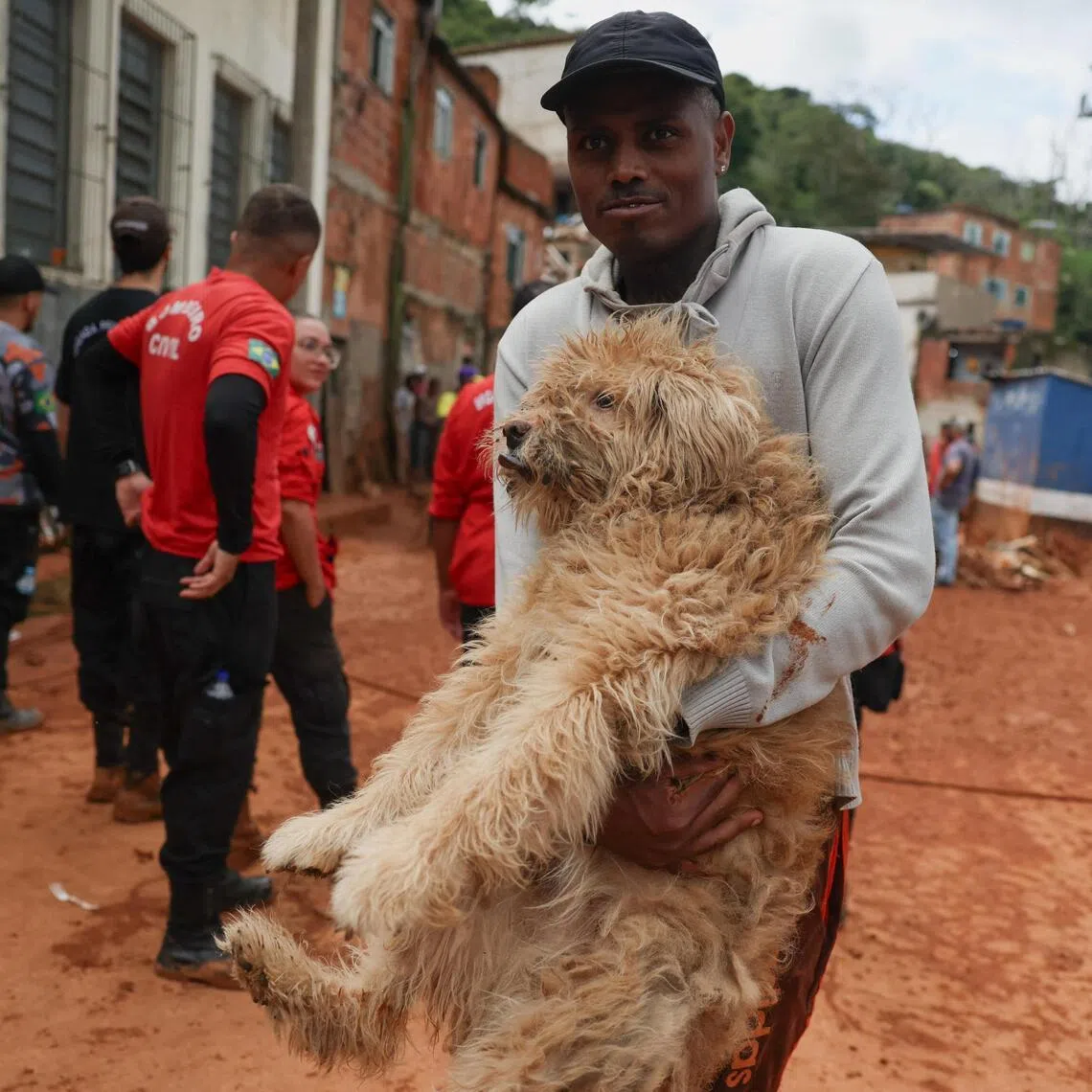 A man carrying a dog as rescue workers search for victims in Juiz de Fora, in Brazil's Minas Gerais state, on Feb 24, after heavy rain caused flooding.
