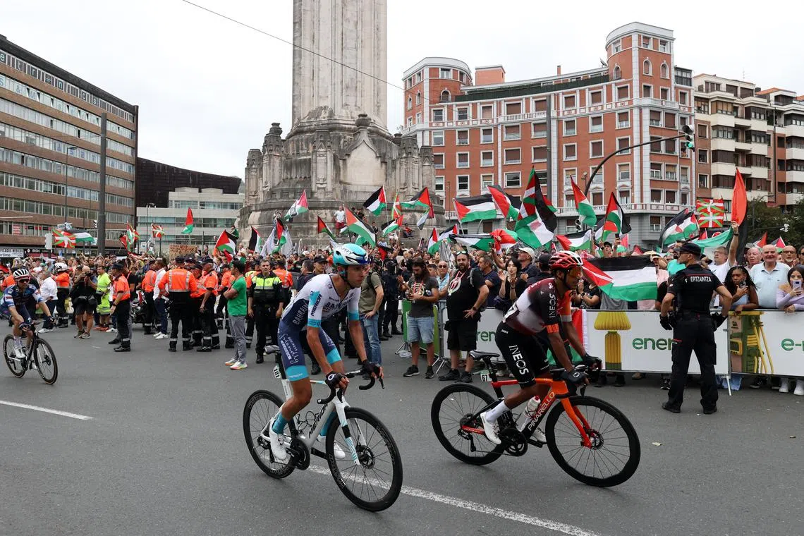 FILE PHOTO: Cycling - Vuelta a Espana - Stage 11 - Bilbao to Bilbao - Bilbao, Spain - September 3, 2025 Riders pass protesters with the flag of Palestine during the neutralised finish to stage 11 REUTERS/Pankra Nieto/File Photo
