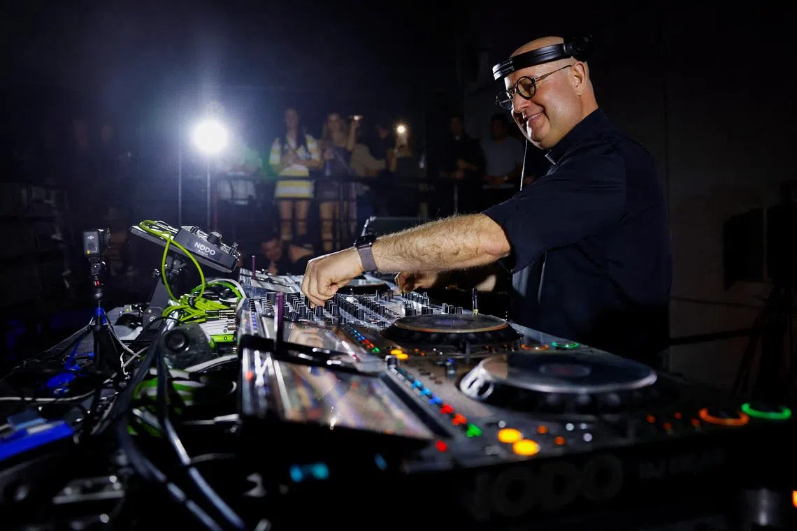 Portuguese Catholic priest Father Guilherme Peixoto, who has gained international recognition as a DJ, particularly among young people, performs on a turntable before a packed dance floor at a venue filled with revelers, in Monterrey, Mexico, December 14, 2025. REUTERS/Daniel Becerril