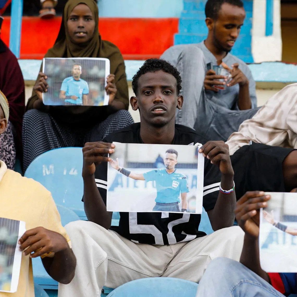 Somalis hold pictures of referee Omar Abdulkadir Artan, who had been expected to officiate matches at the 2026 FIFA World Cup but was refused entry to the United States, at a stadium in Somalia on June 9.