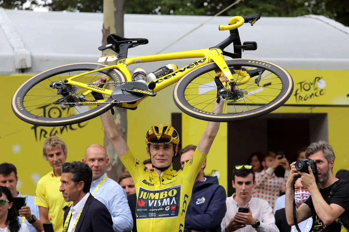 Jumbo-Visma's Danish rider Jonas Vingegaard celebrates victory by lifting his bike at the end the 21st and final stage.
