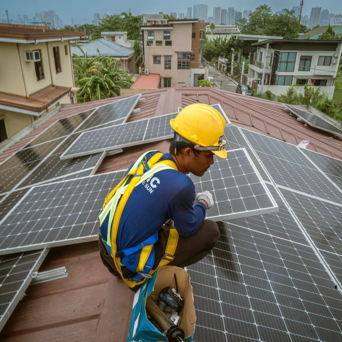 A worker installs a solar power system on a home in Quezon City, The Philippines.
