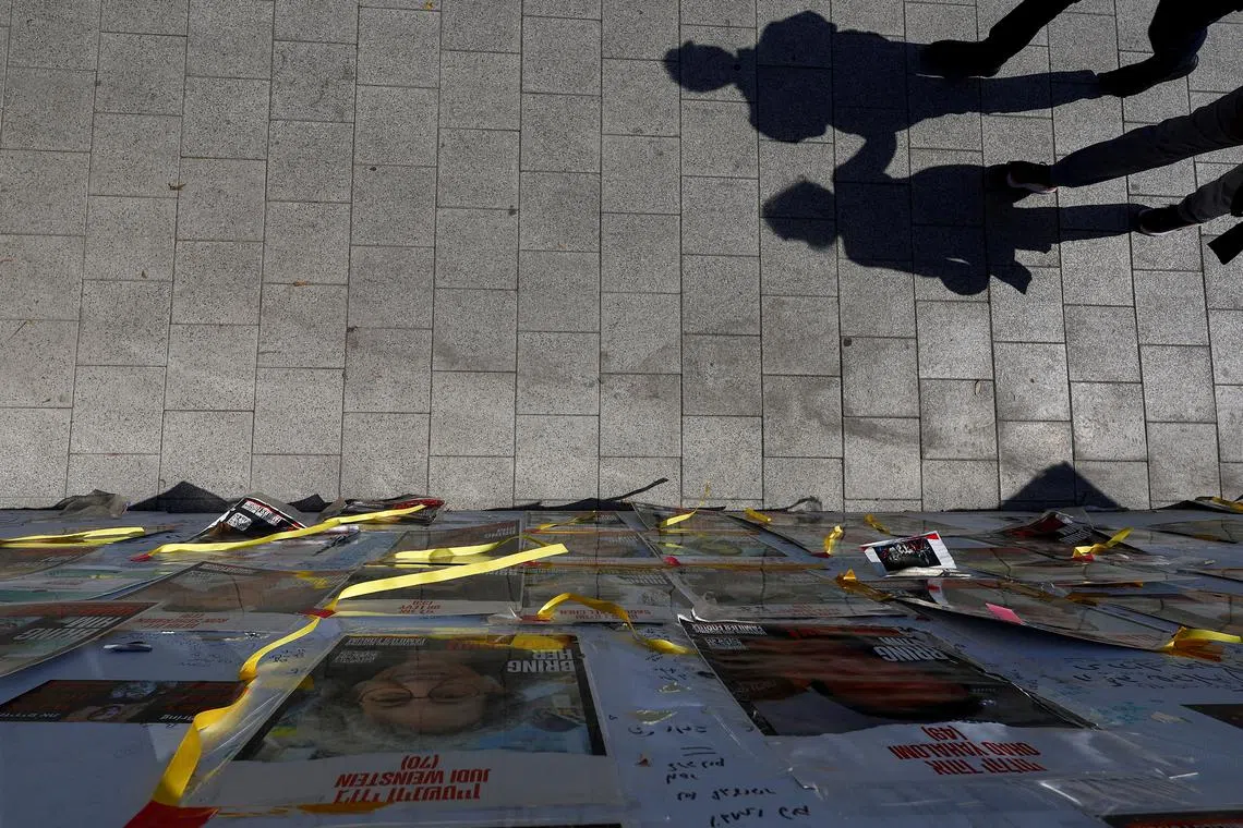 People's shadows are cast as they walk near posters with images of hostages kidnapped in the deadly Oct 7 attack on Israel by the Palestinian Islamist group Hamas, in Tel Aviv, Israel, on April 16, 2024. 