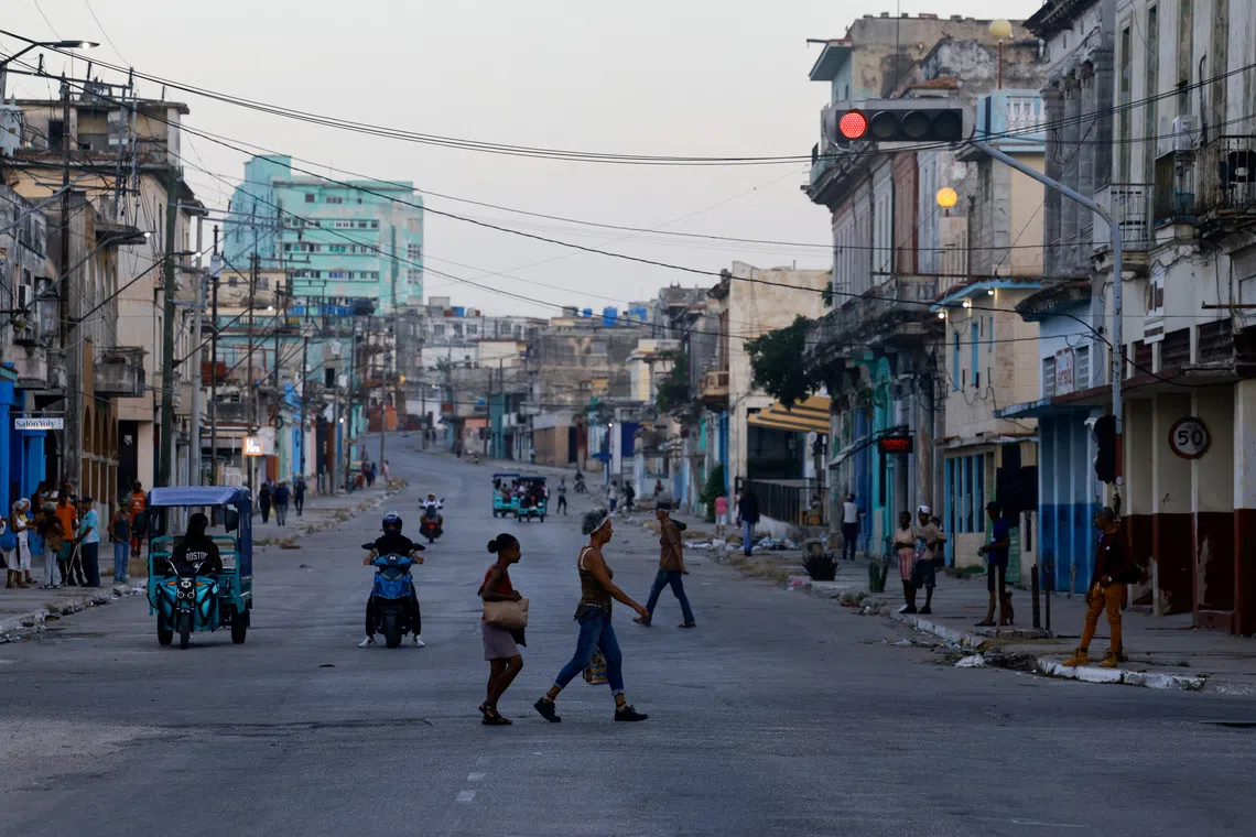 People cross a street as Cuba's national power grid is restored following its collapse, which marked the third major outage in nine days, in Havana, Cuba, July 15, 2026. REUTERS/Norlys Perez