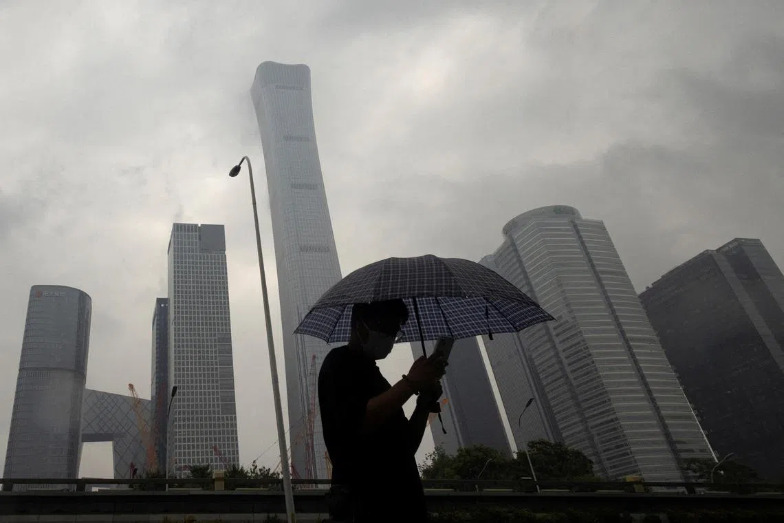 FILE PHOTO: A man walks in the Central Business District on a rainy day, in Beijing, China, July 12, 2023. REUTERS/Thomas Peter/File Photo