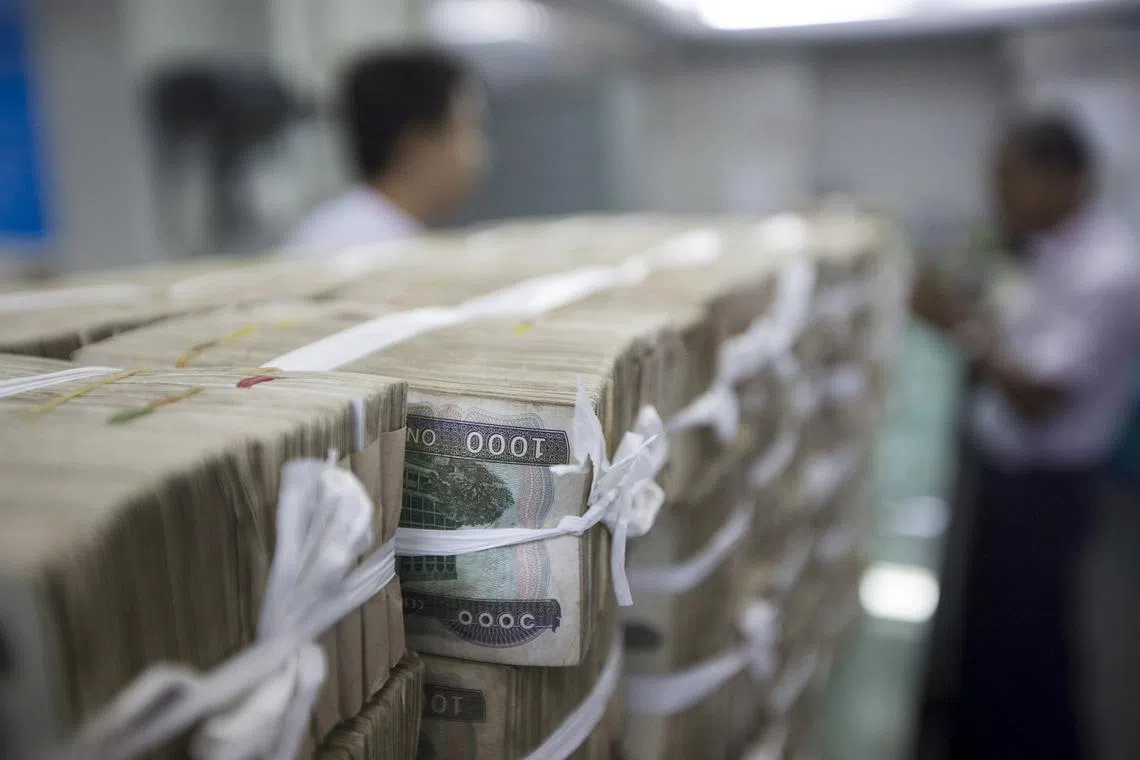 FILE PHOTO: Stacks of Myanmar kyat are seen on the counter before a client collects them, at a bank in Yangon, Myanmar October 19, 2015. REUTERS/Minzayar/File Photo