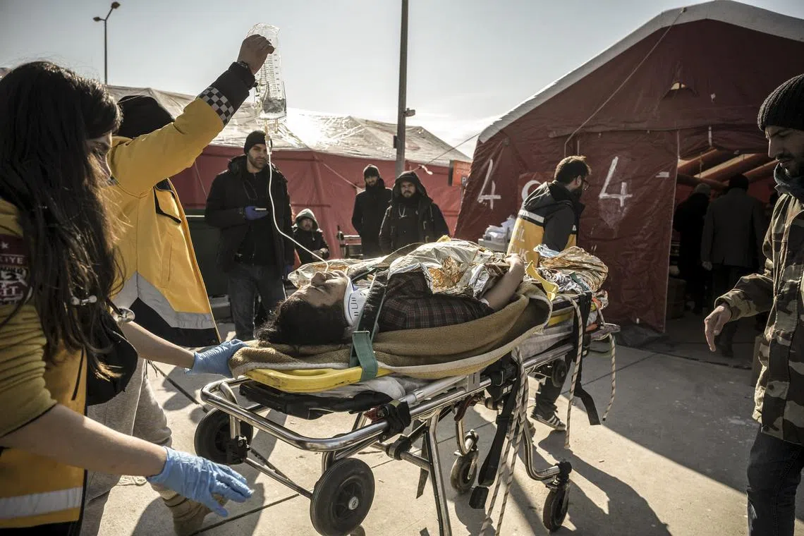 Medical personnel, many of them volunteers, rush a quake victim to a field hospital in Antakya, Turkey, on Friday. The makeshift hospitals – a series of red tents – are manned by local and international medical personnel.
