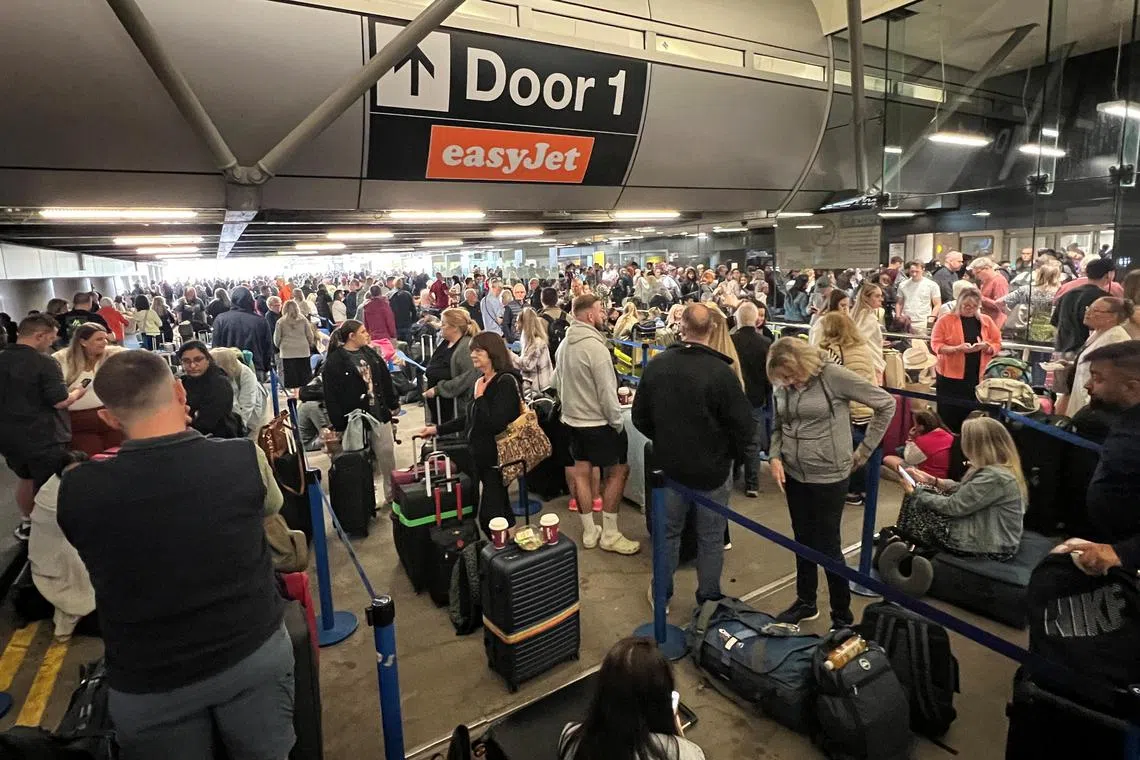Passengers queue outside Terminal 1 after an overnight power cut led to disruptions and cancellations at Manchester Airport on June 23, 2024. 