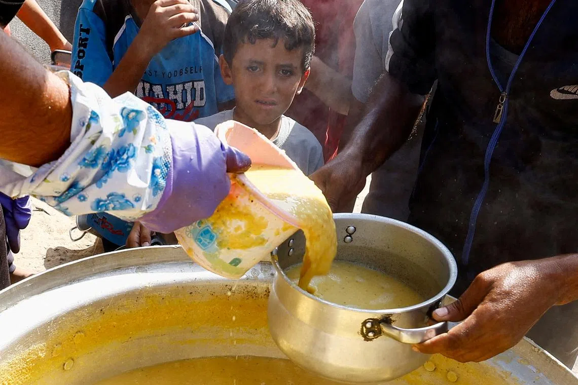 FILE PHOTO: A child looks on as Palestinians gather to receive food cooked by a charity kitchen, amid the Israel-Hamas conflict, in Khan Younis in the southern Gaza Strip, October 16, 2024. REUTERS/Mohammed Salem/File Photo