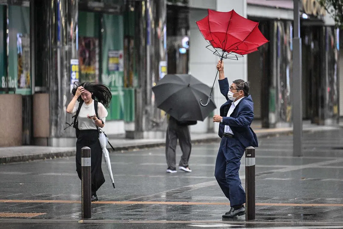 A man holding his umbrella in the wind outside Hakata station in Fukuoka, Japan, on Aug 29, 2024. Japan prepared for its strongest typhoon of the year, with authorities advising tens of thousands of people to evacuate and issuing the highest warning level for wind and storm surges on the main southern island of Kyushu. 
