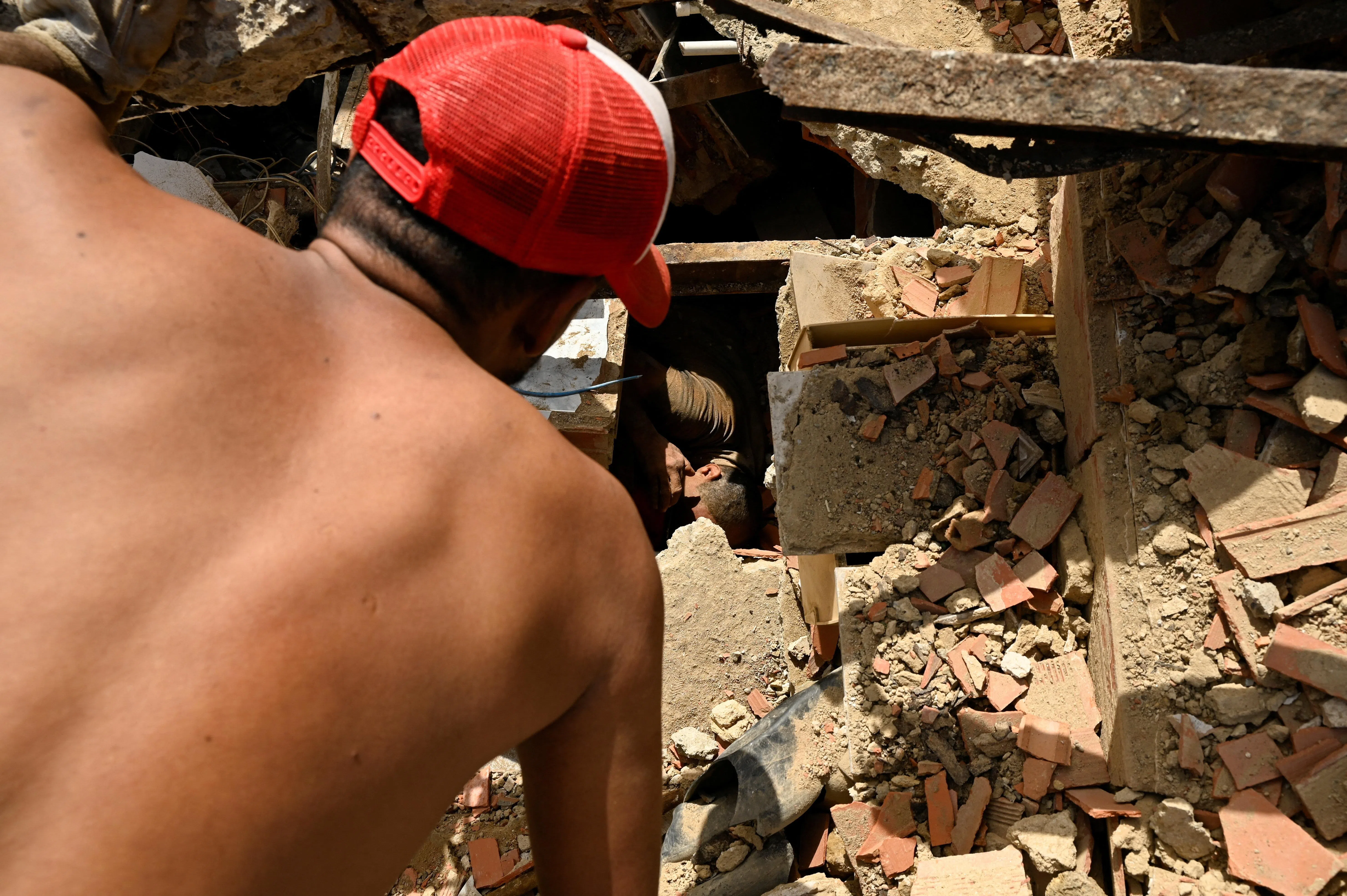 People work to rescue a man trapped under the rubble of a collapsed building, in the aftermath of earthquakes in La Guaira, Venezuela, June 25, 2026. REUTERS/Maxwell Briceno