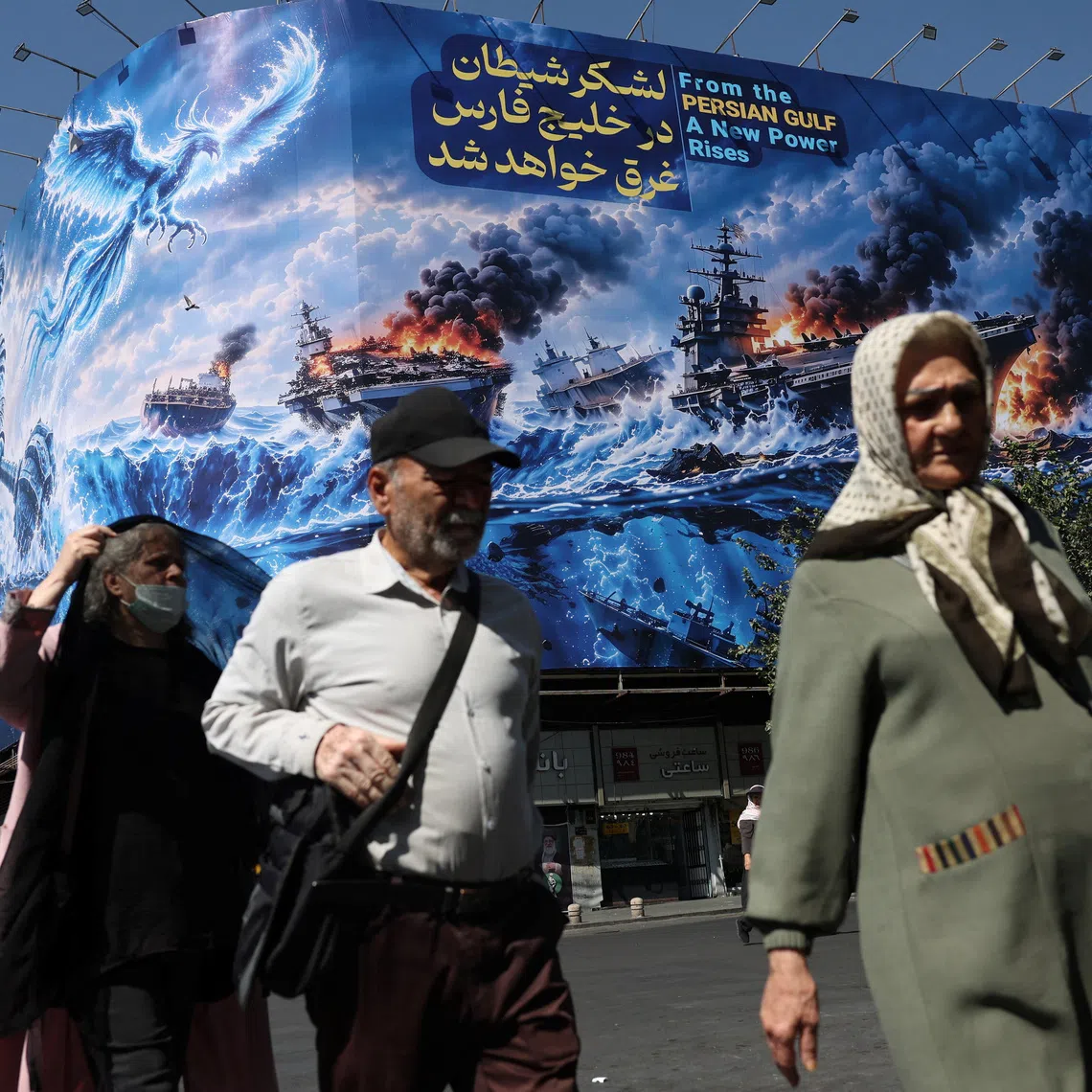 People walk past a billboard about the Strait of Hormuz, on a building in Tehran. Iran’s economy has long struggled with hyperinflation and devaluation of its currency, caused in large part by economic sanctions.