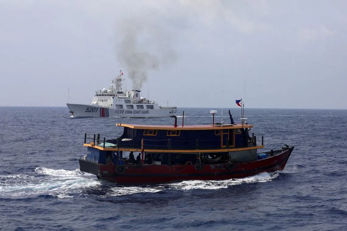 FILE PHOTO: A Philippine supply boat sails near a Chinese Coast Guard ship during a resupply mission for Filipino troops stationed at a grounded warship in the South China Sea, October 4, 2023. REUTERS/Adrian Portugal/File Photo