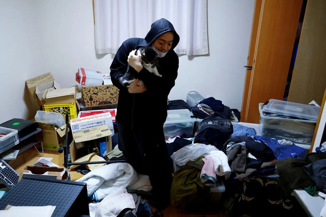 Tomonori Akiyama holding his cat as he shows his house which he is cleaning after it was damaged by the earthquake, in Wajima, Ishikawa Prefecture, Japan, Jan 6, 2024. 