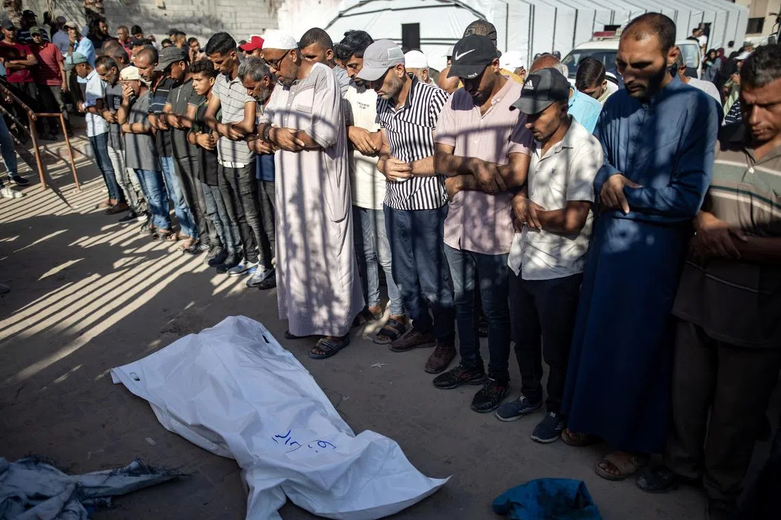 Palestinians pray next to the bodies of their relatives who were killed following an Israeli strike that hit a school.