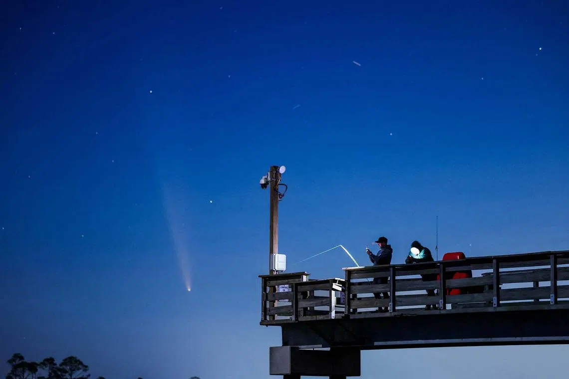 Comet C/2023 A3 (Tsuchinshan-ATLAS) is visible shortly after sunset in the western sky over the Fisherman’s Walk Pier as two men fish, in Tybee Island, Georgia, U.S. October 13, 2024. REUTERS/Sam Wolfe TPX IMAGES OF THE DAY