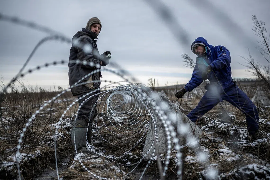 Workers installing razor wire as a part of defence structures near a front line, amid Russia's attack on Ukraine, in the Kharkiv region, Ukraine, Dec 25, 2023. 