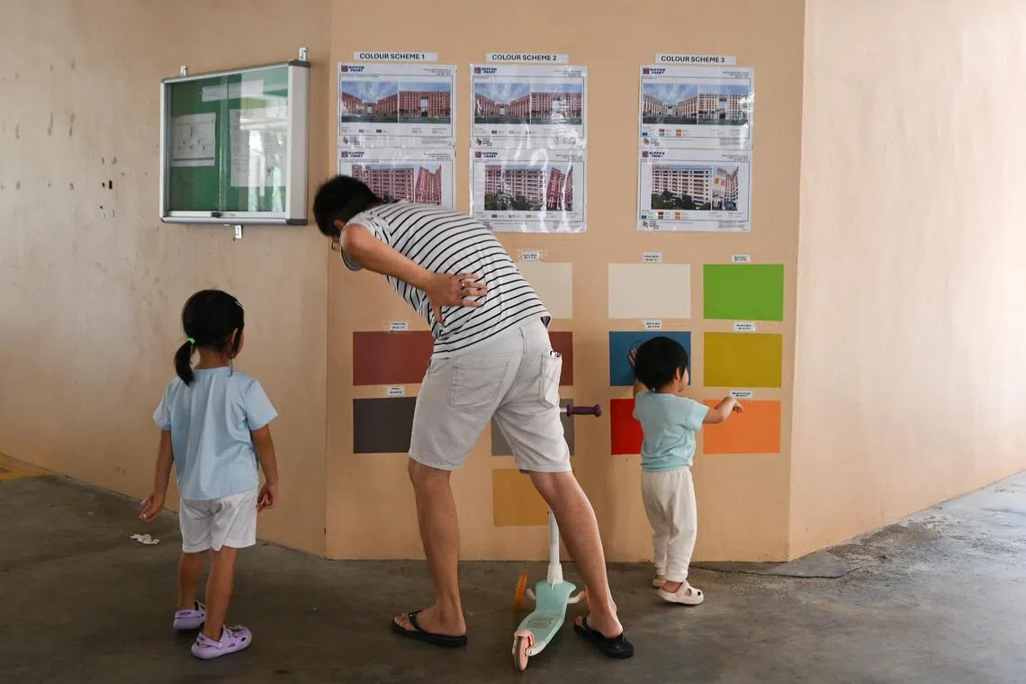 A family looking at the different colour schemes pasted at the void deck of Block 497A Tampines Street 45 on Sept 19.