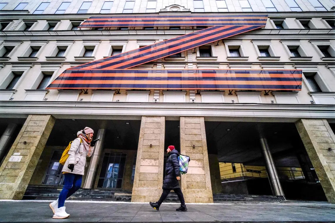People walk past a Moscow theatre building adorned with the letter Z in orange and black, a symbol of support for Russia's invasion of Ukraine.