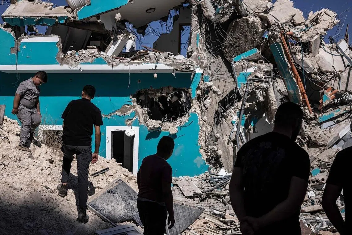 TOPSHOT - Palestinians gather in front of a building containing shops and flats that were demolished by Israeli forces, citing the lack of a building permit, in Anzah, south of the Palestinian city of Jenin in the northern Israeli-occupied West Bank, on July 27, 2026. (Photo by JOHN WESSELS / AFP)
