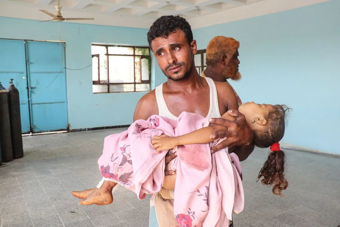 TOPSHOT - A man carries an injured child at a hospital following a reported Houthi drone strike in the Mash'a area of Hays, south of Hodeidah, on August 18, 2026. Yemen, which has been embroiled in more than a decade of civil conflict, last month became the latest country to be dragged into the Middle East war as the Iran-backed Houthis upended the 2022 truce with the Saudi-backed government, ramping up attacks on areas it holds. (Photo by Khaled ZIAD / AFP)