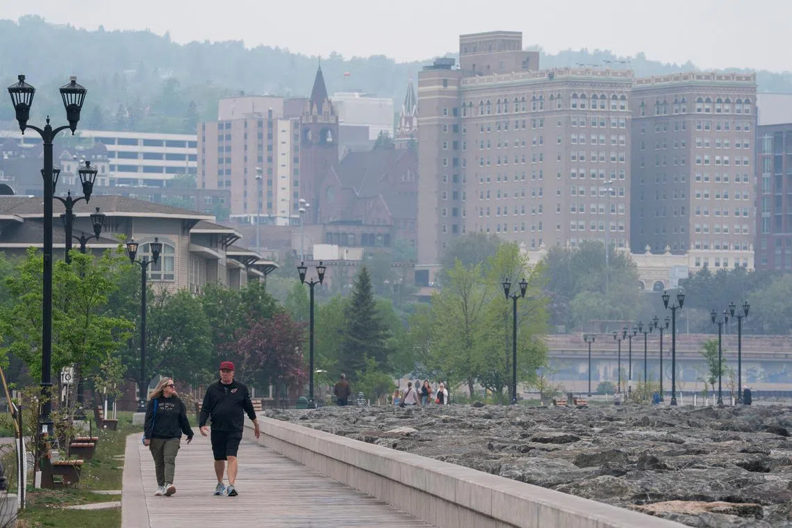 Pedestrians walk along Lake Superior as a haze from Canadian wildfire smoke causes poor air quality in Duluth, Minnesota.