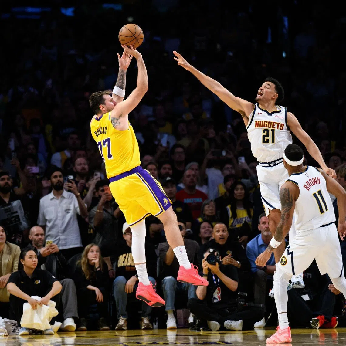 Mar 14, 2026; Los Angeles, California, USA; Los Angeles Lakers guard Luka Doncic (77) shoots a game winning shot while under pressure from Denver Nuggets forward Spencer Jones (21) during overtime at Crypto.com Arena. Mandatory Credit: William Liang-Imagn Images