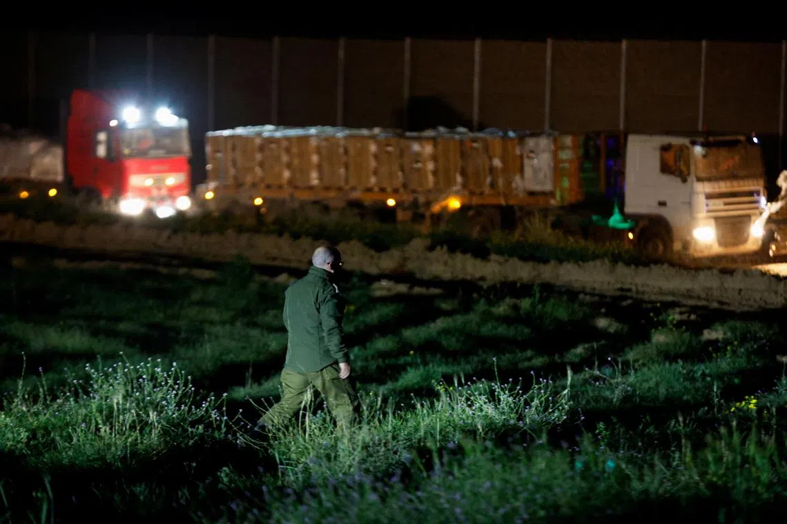 An Israeli soldier walks near the aid trucks with humanitarian supplies waiting by Gate 96, a newly opened entry point allowing quicker access into northern Gaza, in Israel, March 21, 2024. REUTERS/Amir Cohen