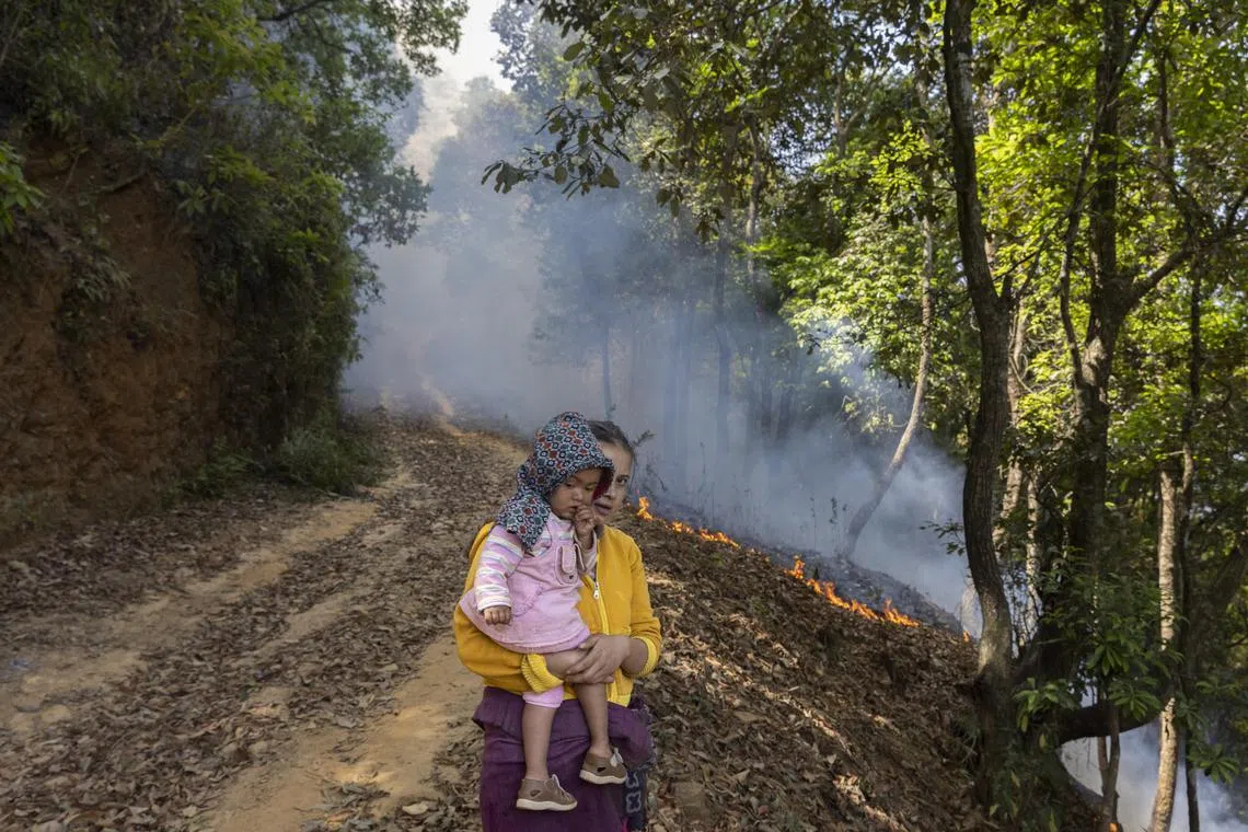 A local woman and a child watch the forest fire near Godawari village, on the outskirts of Kathmandu in Nepal on May 2.