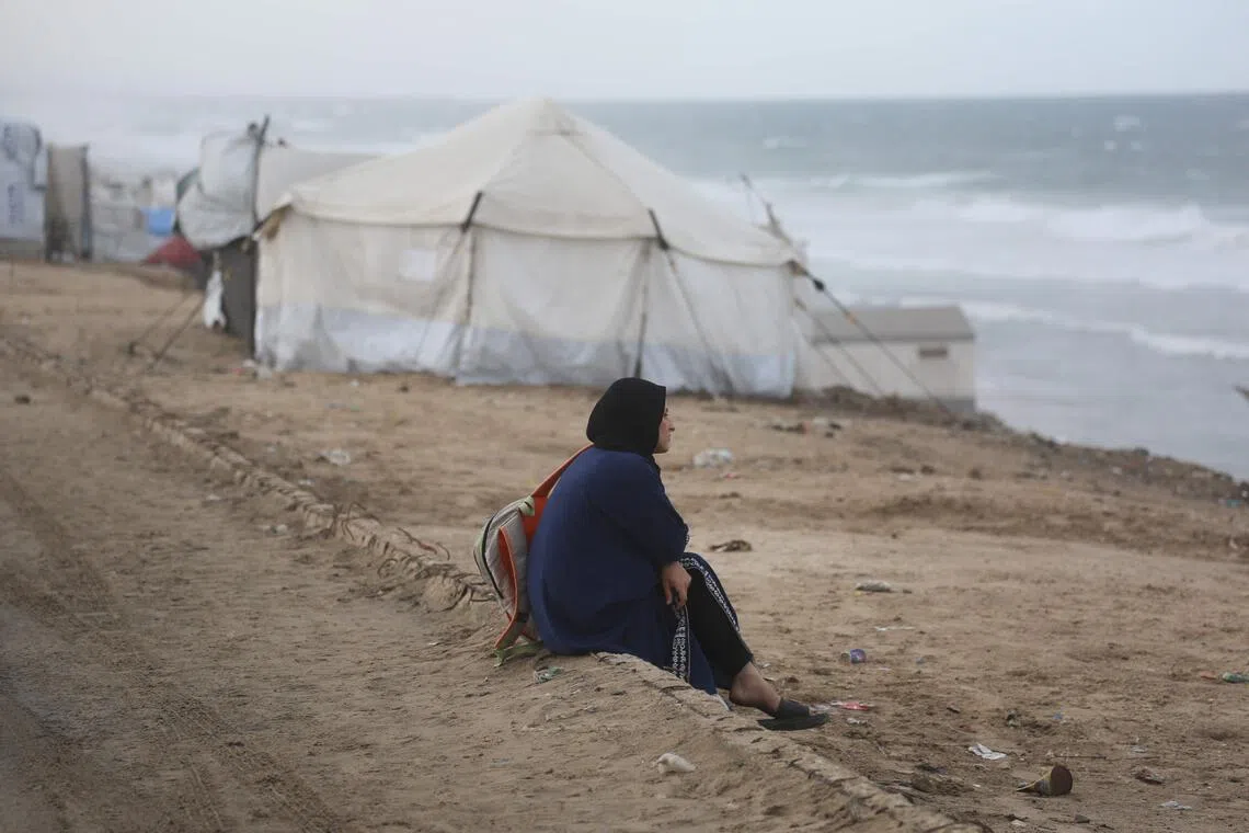 A displaced Palestinian woman sitting on the beach near tents in the central Gaza Strip, on Nov 15, 2025, as a low-pressure system impacts the area. 