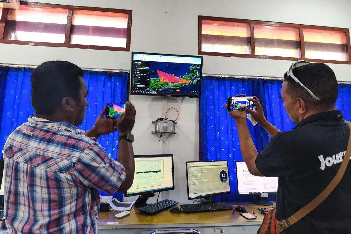 Journalists photograph a screen showing the movement of volcanic ash from Mount Lewotobi Laki-laki at the Meteorology, Climatology and Geophysics Agency (BMKG) office in East Nusa Tenggara.