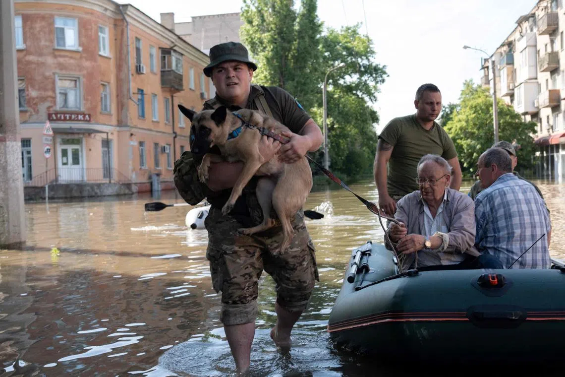 Ukrainian servicemen evacuate local residents from a flooded area in Ukraine's Kherson.