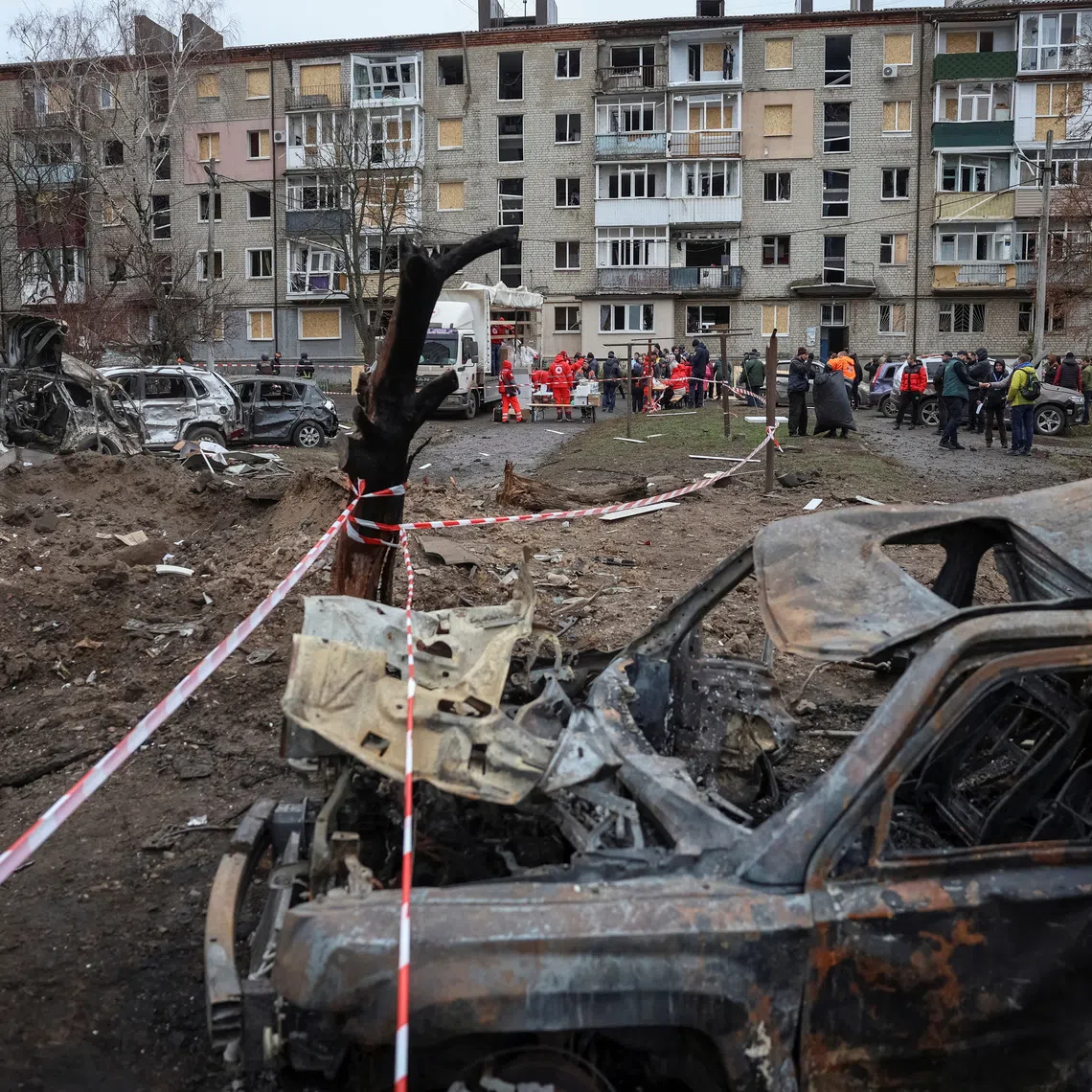 Residents receive humanitarian aid near their apartment building damaged during Russian missile strikes in the Kharkiv region on Nov 17.